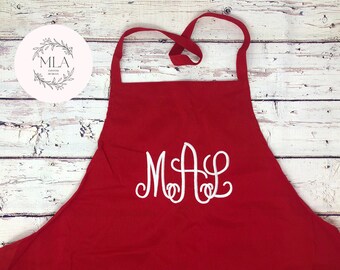 Puede incluir: Delantal de cocina rojo con un monograma bordado en blanco "MAL" en la parte delantera.