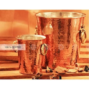 May include: Two hammered copper ice buckets, one large and one small, with decorative handles. 100% copper.