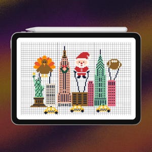 Op de afbeelding: Een digitale tablet met een pixel art kruissteekpatroon van de skyline van New York. Het ontwerp bevat het Vrijheidsbeeld, een kalkoen, het Empire State Building met een krans, de Kerstman, een football en gele taxi's.