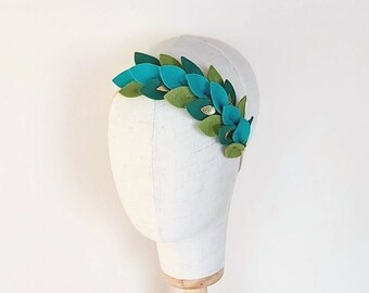 May include: A green and gold felt leaf crown headband. The headband is on a white mannequin head.