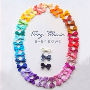 May include: A rainbow assortment of felt baby bows arranged in a circle. The bows are in various colors, including yellow, orange, red, pink, purple, blue, and green. The text "Tiny Classic BABY BOWS" is in the center of the circle.