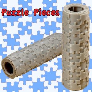 May include: Two gray puzzle-piece-patterned cylindrical objects. One is upright, the other is horizontal. The text "Puzzle Pieces" is at the top in red and blue. The background is a pattern of blue and white puzzle pieces.