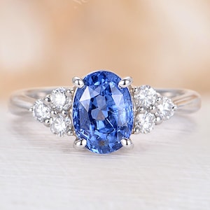 May include: A silver ring with a large oval blue sapphire gemstone surrounded by smaller white diamonds.