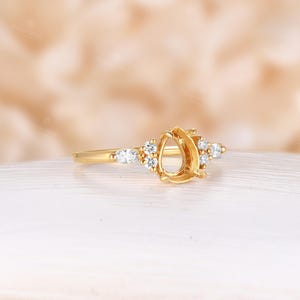 May include: A gold ring setting with a pear-shaped center stone and small round and pear-shaped accent stones.