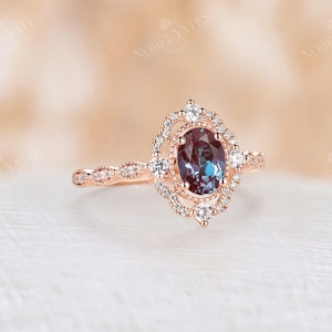 May include: A rose gold engagement ring with a large oval-shaped blue gemstone surrounded by a halo of smaller diamonds. The band is also set with smaller diamonds.