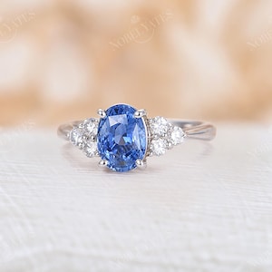 May include: A silver ring with a large oval blue sapphire gemstone surrounded by smaller round white diamonds.