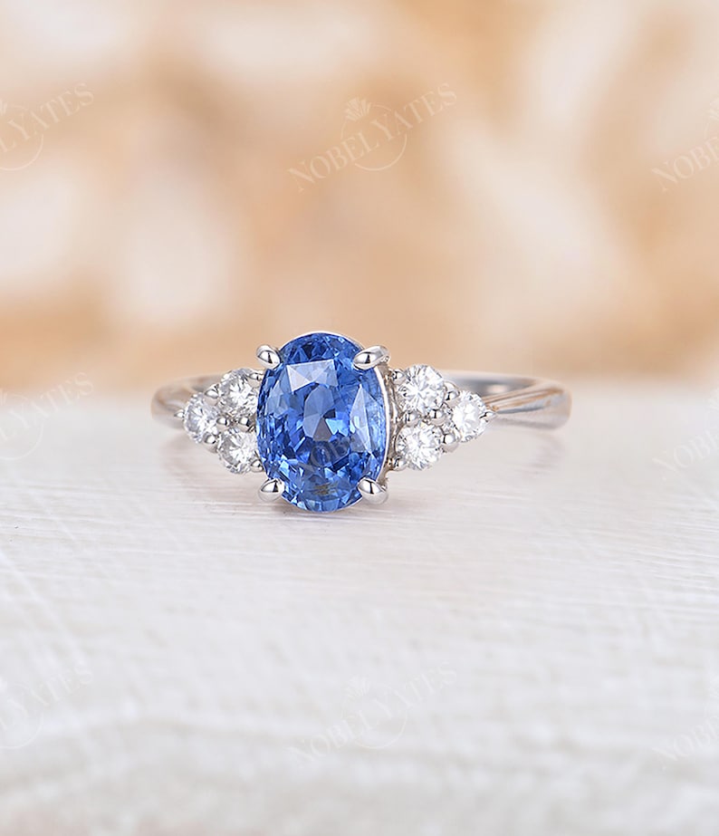 May include: A silver ring with a large oval blue sapphire gemstone surrounded by smaller round white diamonds.