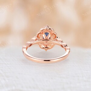 May include: A rose gold engagement ring with a blue gemstone surrounded by smaller white gemstones. The ring has a delicate, intricate design.