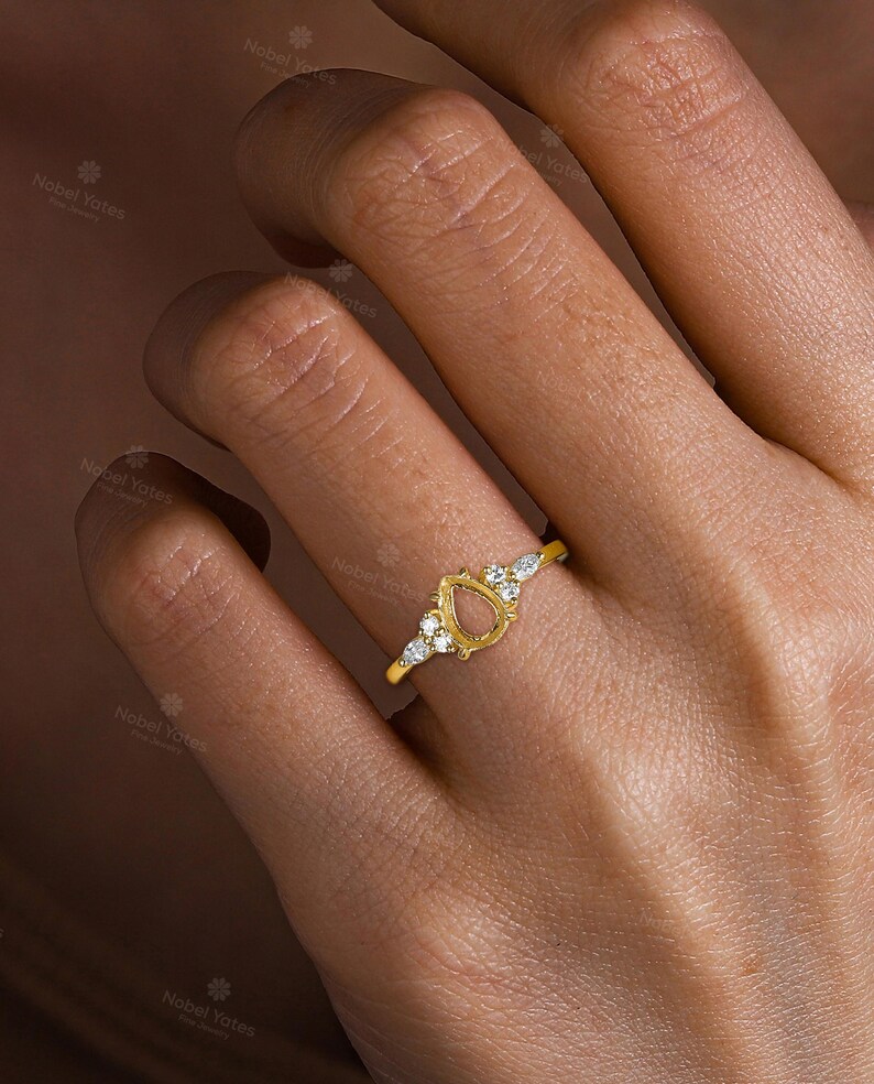 May include: A gold ring with a pear-shaped setting and small diamonds around the band.