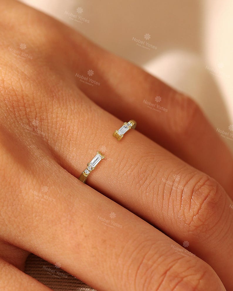 A close-up of a person's hand wearing a gold ring with two diamond-encrusted pieces.
