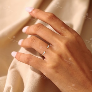 A close-up of a hand wearing a ring with two small stones.