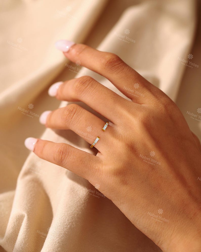 A close-up of a hand wearing a ring with two small stones.