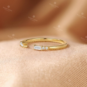 A gold ring with a diamond accent sits on a textured fabric surface.
