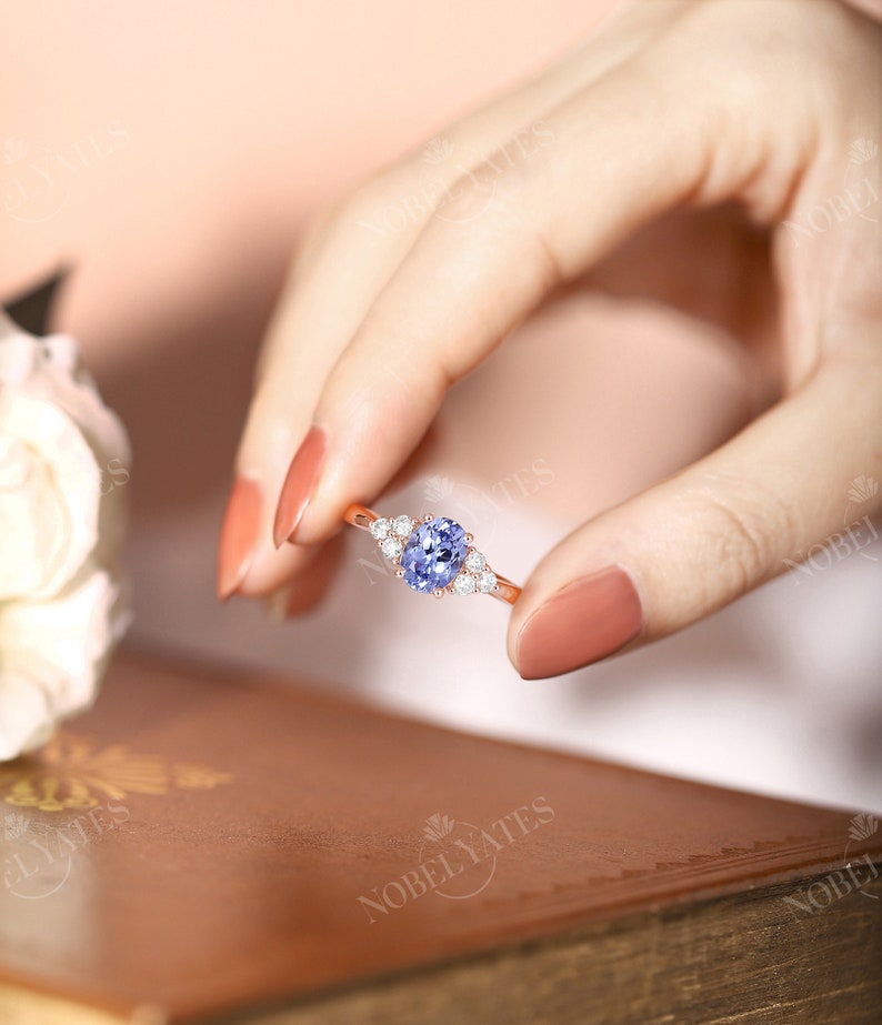 May include: A rose gold ring with a light blue oval gemstone surrounded by smaller clear gemstones.