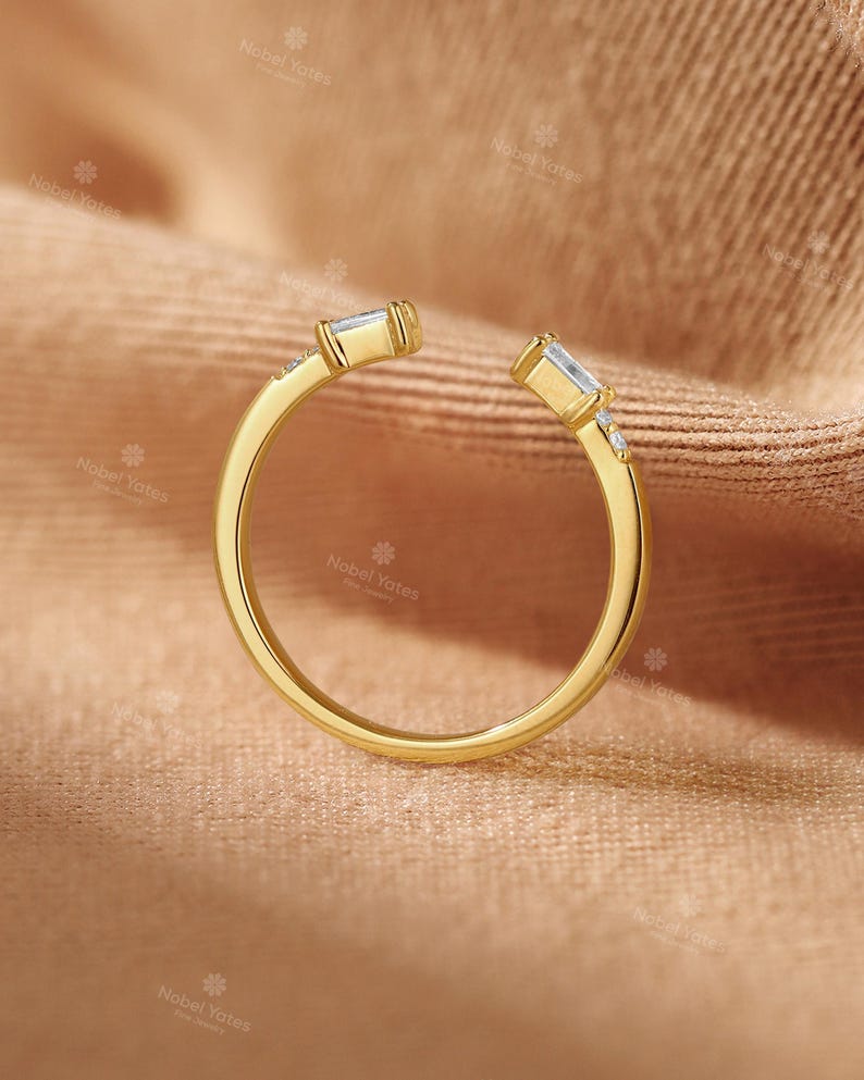 A gold ring with a unique design sits on a textured fabric surface.
