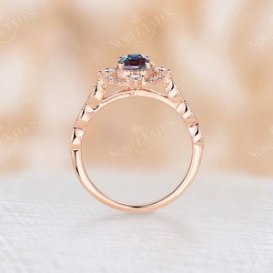 May include: A rose gold engagement ring with a halo setting featuring a blue gemstone surrounded by smaller clear gemstones. The band is adorned with a delicate, textured design.