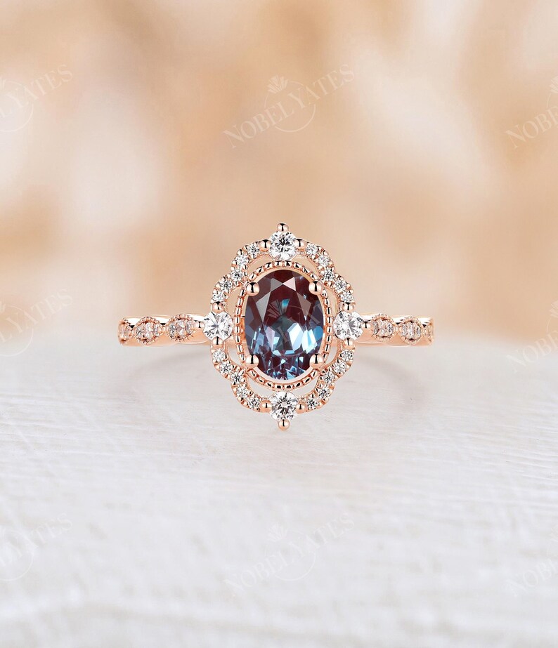 May include: A rose gold engagement ring with a large oval-shaped blue gemstone surrounded by a double halo of smaller diamonds. The band is also set with smaller diamonds.