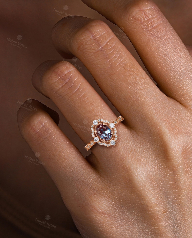 May include: A rose gold ring with a large oval-shaped gemstone surrounded by smaller diamonds. The ring is set in a delicate, ornate design.