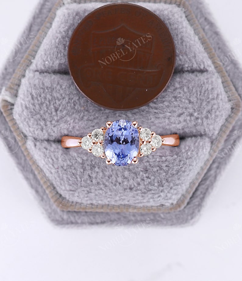 May include: A rose gold engagement ring with a light blue oval sapphire center stone and a halo of smaller round diamonds.