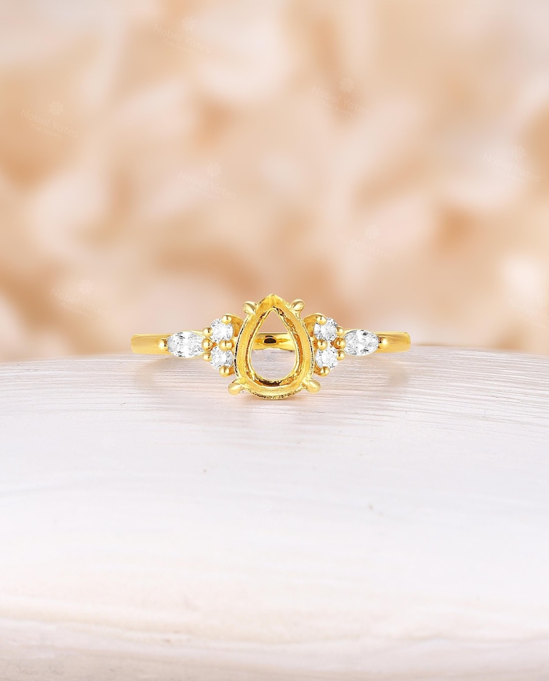 May include: A gold ring with a pear-shaped setting and small round diamonds on the band.
