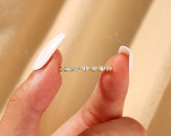 May include: A gold band ring featuring a series of alternating marquise-cut and round-cut clear stones set along the top. The metal has a polished yellow finish, and the stones are arranged in a repeating pattern across the visible front section.