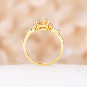 May include: A gold ring with a center setting for a large gemstone and smaller accent stones on either side.