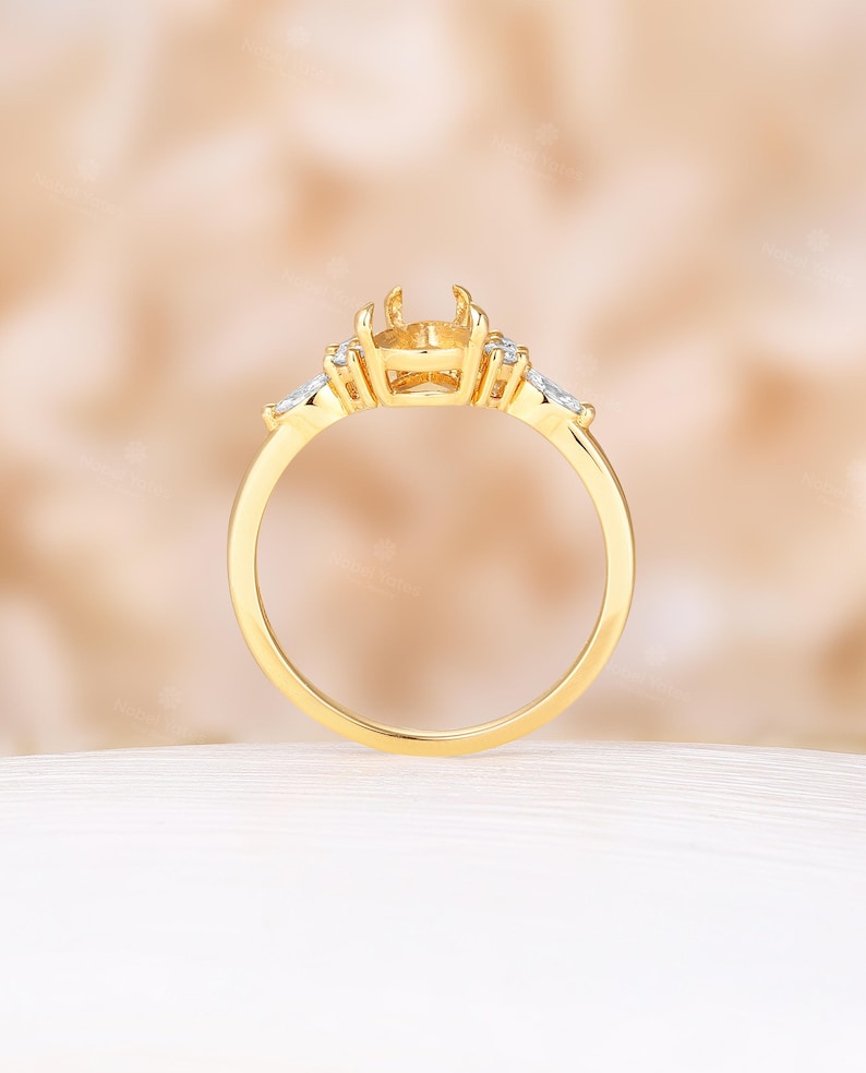 May include: A gold ring with a center setting for a large gemstone and smaller accent stones on either side.