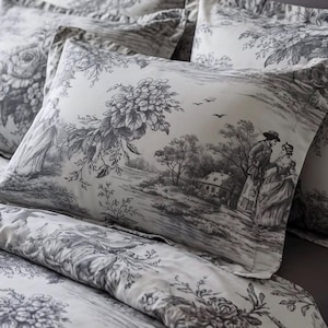 May include: A bedding set featuring a white fabric base with a dark gray toile de jouy print. The pattern depicts pastoral scenes with figures in period clothing, floral bouquets, and trees. The set includes a duvet cover and matching pillowcases.