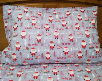 May include: A gray pillowcase with a repeating pattern of Santa Claus characters, Christmas trees, and the words "Ho ho ho".
