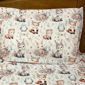 May include: White bedding with a repeating pattern of foxes, bunnies, birds, and flowers. The bedding is made of soft, comfortable fabric and features a whimsical woodland theme.