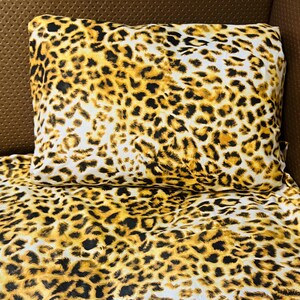 May include: A rectangular pillow and a matching flat sheet featuring a bold leopard print pattern. The fabric displays a repeating design of black and dark brown spots set against a vibrant golden yellow and white background, creating a cohesive look.