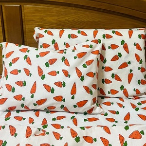 May include: White bedding with a pattern of orange carrots with green leaves. Two white pillowcases with the same carrot pattern are on top of the bedding.