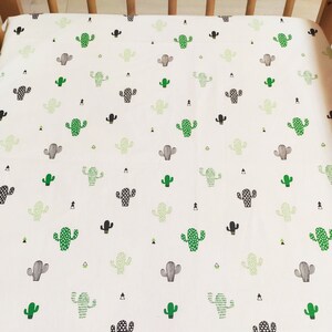 May include: White fitted crib sheet with a repeating pattern of green and black cactus illustrations.
