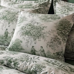 Può includere: Un set di biancheria da letto con base in tessuto bianco e un motivo toile de jouy verde ripetuto. Il design raffigura bouquet di fiori, alberi e figure in abiti d'epoca. Il set include diversi cuscini quadrati e un copripiumino abbinato.