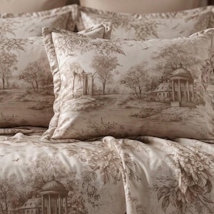 May include: A bedding set featuring two rectangular pillows and a matching comforter in a light beige fabric with a brown monochromatic toile print. The pattern depicts detailed pastoral landscapes with classical buildings, trees, and birds.