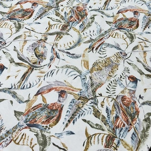 Puede incluir: Tela blanca con un patrón repetitivo de pájaros y hojas coloridos. Los pájaros están detallados con plumas marrones, azules y verdes. Las hojas son verdes y marrones.