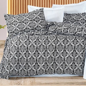 May include: A black and white patterned duvet cover with a white bed skirt. The duvet cover has a damask pattern.