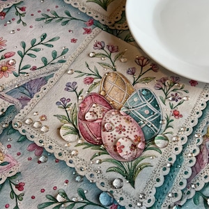 Può includere: Primo piano di un'elegante tovaglietta a tema pasquale con quattro uova decorate. Le uova sono rosa, oro e verde acqua, con motivi floreali e geometrici. La tovaglietta presenta un motivo floreale e un bordo in pizzo smerlato.