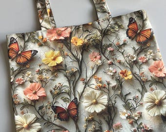 May include: A floral tote bag featuring a pattern of orange butterflies and various flowers in shades of peach, yellow, and white. The bag has a cream-colored background. The handles and the bag's body share the same design.
