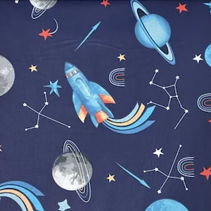 Può includere: Un tessuto blu navy con un motivo ripetuto di razzi, pianeti, stelle e arcobaleni. I razzi sono blu con fiamme arancioni e scie gialle e blu. I pianeti sono blu, grigi e bianchi. Le stelle sono rosse, bianche e gialle. Gli arcobaleni sono blu, gialli e rossi.