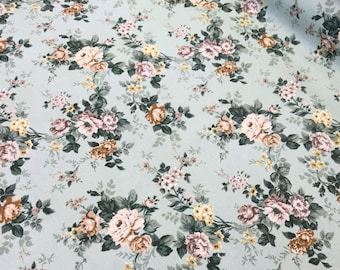 Puede incluir: Una tela azul claro con un patrón floral con rosas rosas, marrones y amarillas. La tela tiene un aspecto vintage y es perfecta para proyectos de manualidades.