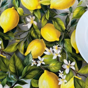 Pode incluir: Uma toalha de mesa branca com um padrão de árvore de limão. A toalha de mesa apresenta limões amarelos, folhas verdes e flores brancas.