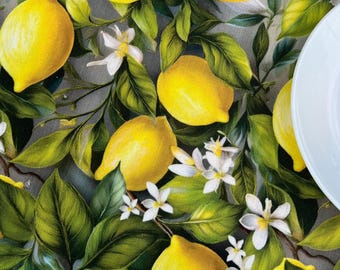 May include: A white tablecloth with a lemon tree pattern. The tablecloth features yellow lemons, green leaves, and white flowers.