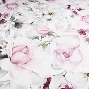 以下が含まれることがあります： ピンクのバラ、緑の葉、紫の花が描かれた水彩画の花柄の白い布地です。