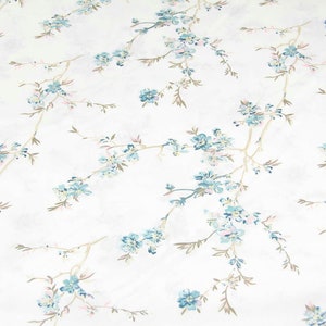 Könnte beinhalten: Weißer Stoff mit einem zarten Blumenmuster mit kleinen blauen Blüten und braunen Zweigen. Das Muster wiederholt sich über den gesamten Stoff.