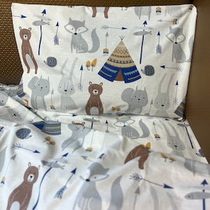 May include: White bedding with a woodland animal print. The print features foxes, bears, rabbits, and arrows. The bedding is made of soft, comfortable fabric.
