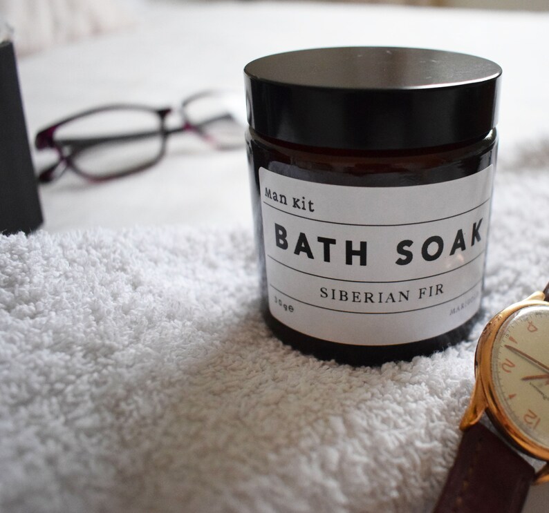 May include: A brown glass jar with a black lid and a white label that reads "Man kit Bath Soak Siberian Fir".