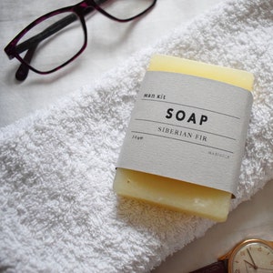 May include: A white bar of soap with a label that reads "Man Kit Soap Siberian Fir 30g Margo & Co."
