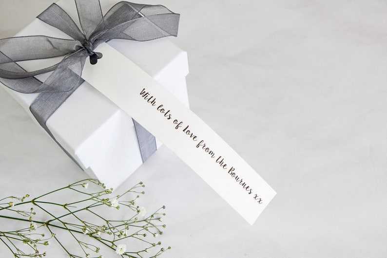 Puede incluir: Una caja de regalo blanca con una cinta gris y una etiqueta de regalo blanca que dice "With lots of love from the Bournes xxx".
