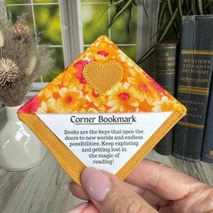 May include: A yellow and orange fabric bookmark with a heart-shaped design and the text "Corner Bookmark" and a quote about books being keys to new worlds.